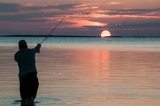 Fly fisherman casting into the setting sun in Florida Bay, Florida