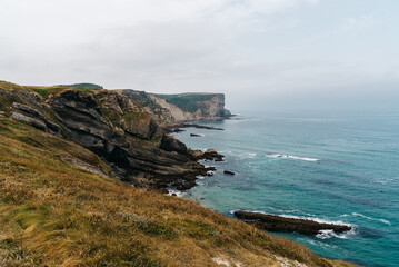 Cliffs surrounding the Beach of Antuerta in Ajo, Trasmiera, Cantabria, Spain. The coast is traversed by a hiking trail that runs through stunning scenery.