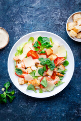 Caesar salad with shrimp, iceberg lettuce, croutons, parmesan cheese and tomatoes with caesar dressing. Blue table background, top view