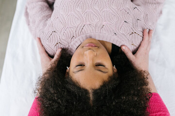 Multiracial Black girl getting craniosacral therapy inside clinic