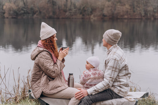 Parents and a little girl are relaxing in a spring park near the river