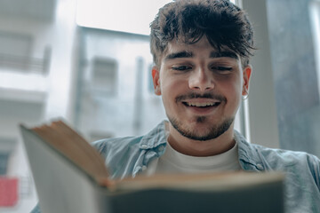 young man reading a book or studying at home
