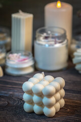 Beautiful white handmade candles of different shapes and sizes on a wooden background