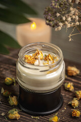 Obraz na płótnie Canvas Beautiful handmade fragrant candle with yellow flower buds in a glass jar on the wooden background