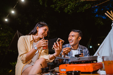 the guy in plaid shirt looking at the woman in orange stripped shirt that sitting beside him and drinking