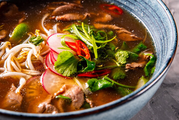 Soup Pho Bo in bowl on gray stone table