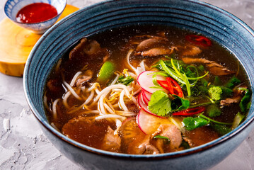 Soup Pho Bo in bowl on gray stone table