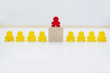 Wooden figure standing on a cube higher than others - concept of leadership or hierarchy