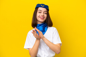 Airplane stewardess Ukrainian woman isolated on yellow background applauding after presentation in a conference