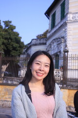 Portrait of a young Asian woman smiling. The placid lake and city range in the background. Beautiful sunset colors in the environment.