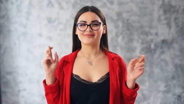Caucasian girl in gray studio background fingers crossed close eyes pray hope wish woman waiting for a miracle pray ask God for help success luck believe trust expect victory beg victory dreamy desire