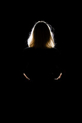 Woman in front of a light source in a black room, only the outlines can be made out..