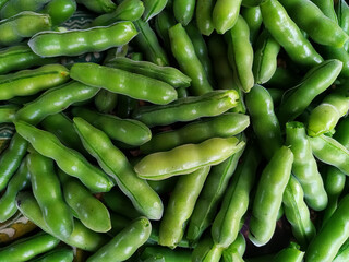 Green broad beans on a market stall, close-up, top view