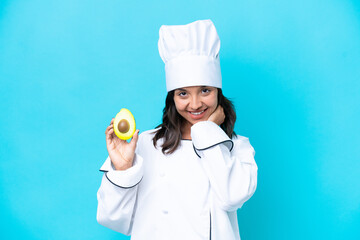 Young hispanic chef woman holding avocado isolated on blue background laughing