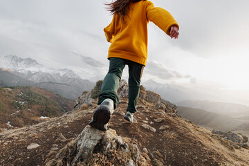 Sporty young girl runs high in mountains. Active tourism concept - obrazy, fototapety, plakaty
