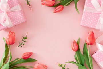 Woman day present concept. Flat lay photo of gift boxes and tulips flowers on pastel pink background with empty space in the middle. Holiday card idea.