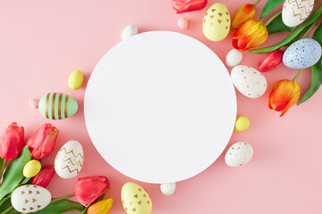 Easter decorations concept. Top view photo of white circle red tulips flowers colorful eggs on isolated pastel pink background with blank space. Easter card idea