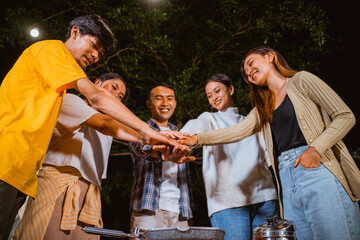 a group of people doing high fived together at the night while camping at the camp site
