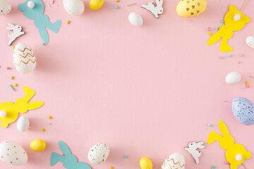 Easter decor concept. Top view photo of yellow white blue eggs cute rabbits easter bunny toppers and sprinkles on pastel pink background with empty space in the middle