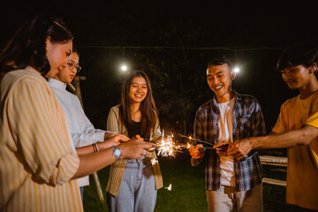 a group of people playing with the fireworks happily and standing in circle while camping at the camp site