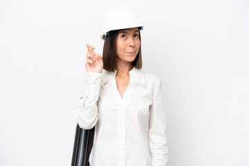 Young architect woman with helmet and holding blueprints isolated on white background with fingers crossing and wishing the best