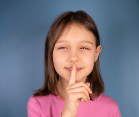 Fototapeta premium girl showing a finger at her closed mouth, a symbol or sign of silence or quiet