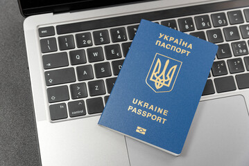 Ukrainian passport on laptop keyboard. Top view. Online registration for Ukrainians. Online visa or immigration for citizens of Ukraine