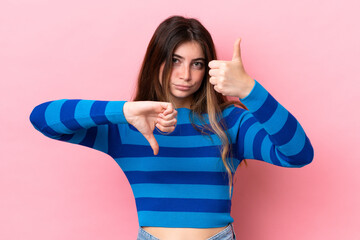 Young caucasian woman isolated on pink background making good-bad sign. Undecided between yes or not