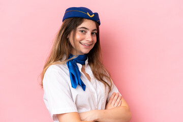 Airplane stewardess caucasian woman isolated on pink background with arms crossed and looking forward