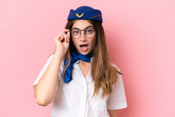 Airplane stewardess caucasian woman isolated on pink background with glasses and surprised