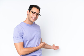 Young caucasian man isolated on white background extending hands to the side for inviting to come
