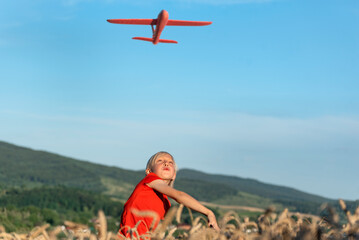 Boy launch model airplane into the sky. Red toy plane against blue sky. Happy carefree childhood.