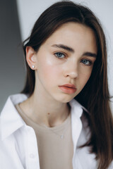 stylish portrait of a young 15-year-old model girl with natural light in a spacious photo studio