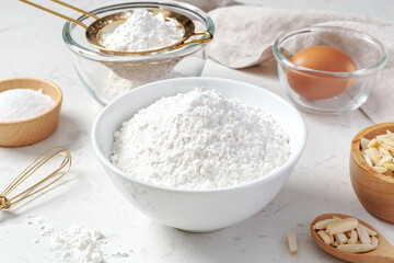 Flour in white bowl with cake or bakery ingredients on marble kitchen table