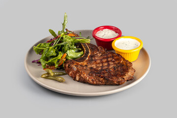 Ribeye steak on a plate with salad and sauce