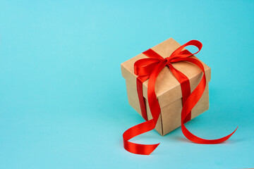 craft gift box with red flying ribbon on blue background isolated