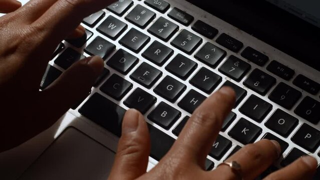 A tight angle of an asian woman typing on a computer laptop keyboard