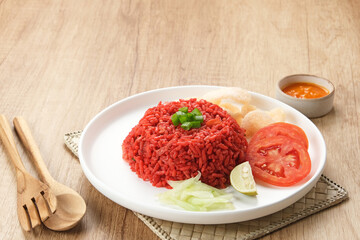 Nasi Goreng Merah, traditional food from Makassar, Indonesia. Fried rice with tomato sauce, shrimp, meatballs and egg. Served with pickled cucumber, chili sauce and lime
