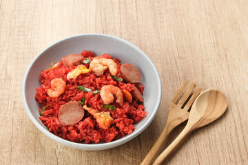 Nasi Goreng Merah, traditional food from Makassar, Indonesia. Fried rice with tomato sauce, shrimp, meatballs and egg. Served with pickled cucumber, chili sauce and lime
