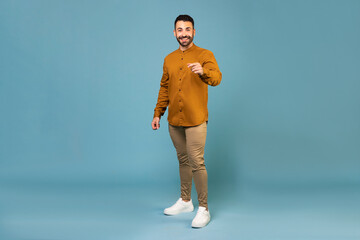 Fototapeta na wymiar Hey or attention. Full length italian european man in casual outfit standing over blue background studio shot copy space
