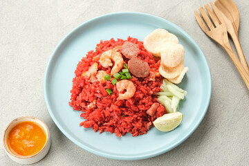 Nasi Goreng Merah, traditional food from Makassar, Indonesia. Fried rice with tomato sauce, shrimp, meatballs and egg. Served with pickled cucumber, chili sauce and lime
