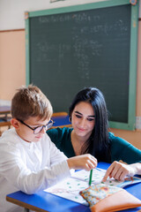 Una maestra svolge delle attività educative con un alunno in classe a scuola