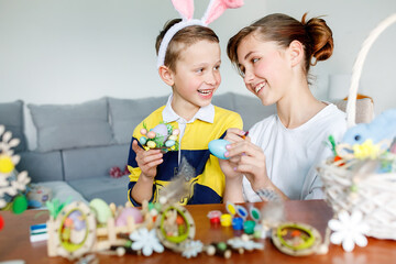 Happy brother and sister look at each other and laugh, they prepare festive decor at the table, preparations for Easter, family traditions.