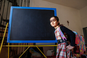 Alunna con zaino e vestito a quadri passa davanti alla lavagna della classe di una scuola