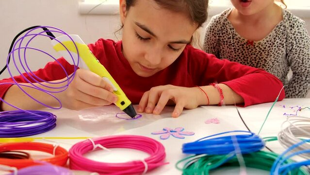 The child draws with a 3D pen. Selective focus.
