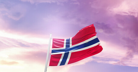 Waving Flag of Norway in Blue Sky. The symbol of the state on wavy cotton fabric.