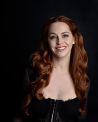 Naklejka premium close up portrait of beautiful woman with long red hair wearing sheer corset top. variety of facial expressions, Isolated on dark studio background with moody silhouette lighting.