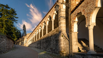 Beautiful cobblestone alley and colonnade under sunset light. Italian classic architecture, Udine...