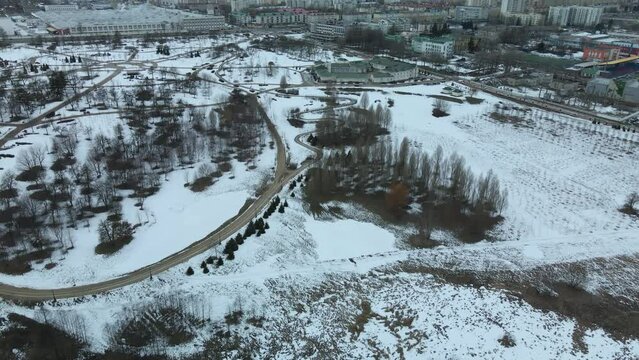 A winding bike path in a city park. City park in winter. Snow lies on the ground. Overcast weather. Aerial photography.
