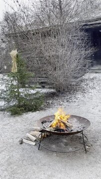 Fire in a brazier or bowl as the snow is falling at winter time conveys warmth and coziness during the cold months of the year. The wooden house in the background reminds of the old Viking dwelling